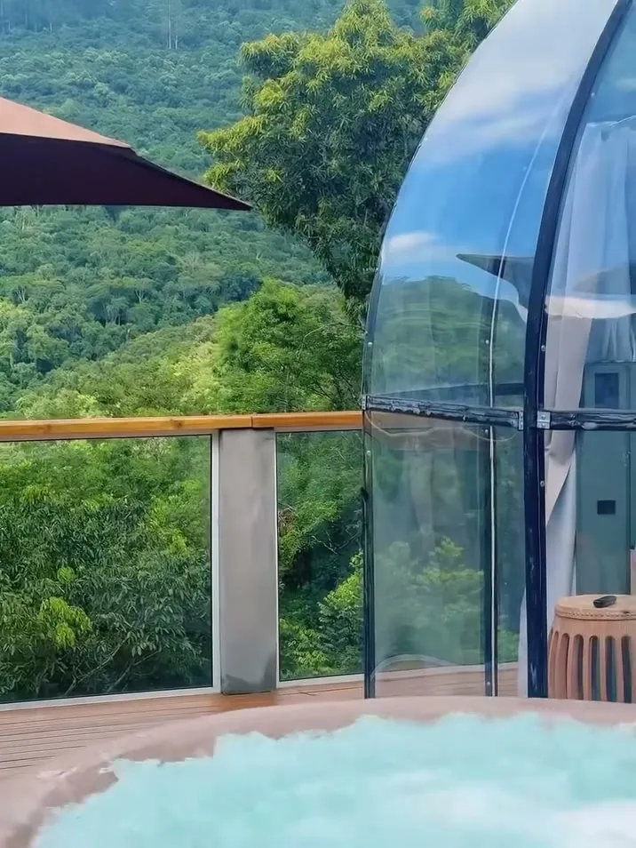 Spa de hidromassagem no deck, ao lado do domo, com a mata em volta