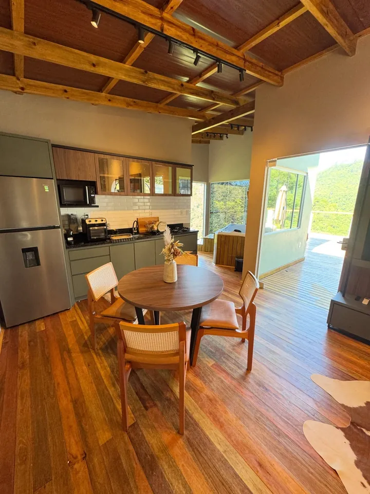 Cozinha e mesa de refeições da casa de apoio, com forro de madeira