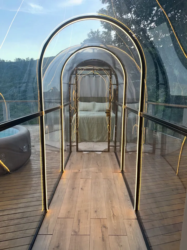 Túnel de vidro da Cabana Cúpula, com arcos de luz dourada, levando ao domo do quarto
